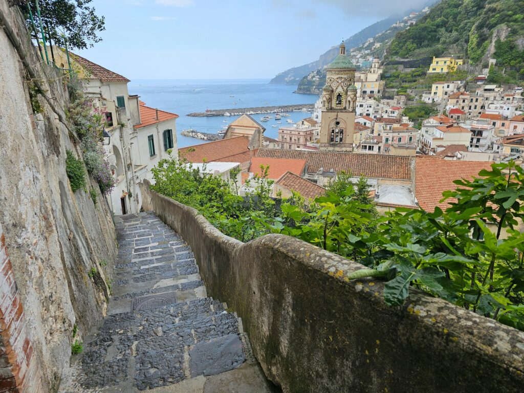 Narrow stone stairway descending toward Amalfi and the sea.
